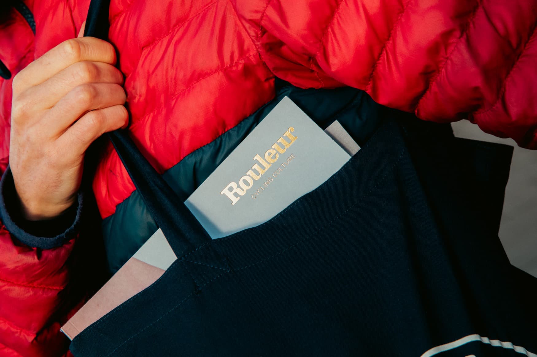 A Rouleur magazine tucked into the pocket of a red down jacket